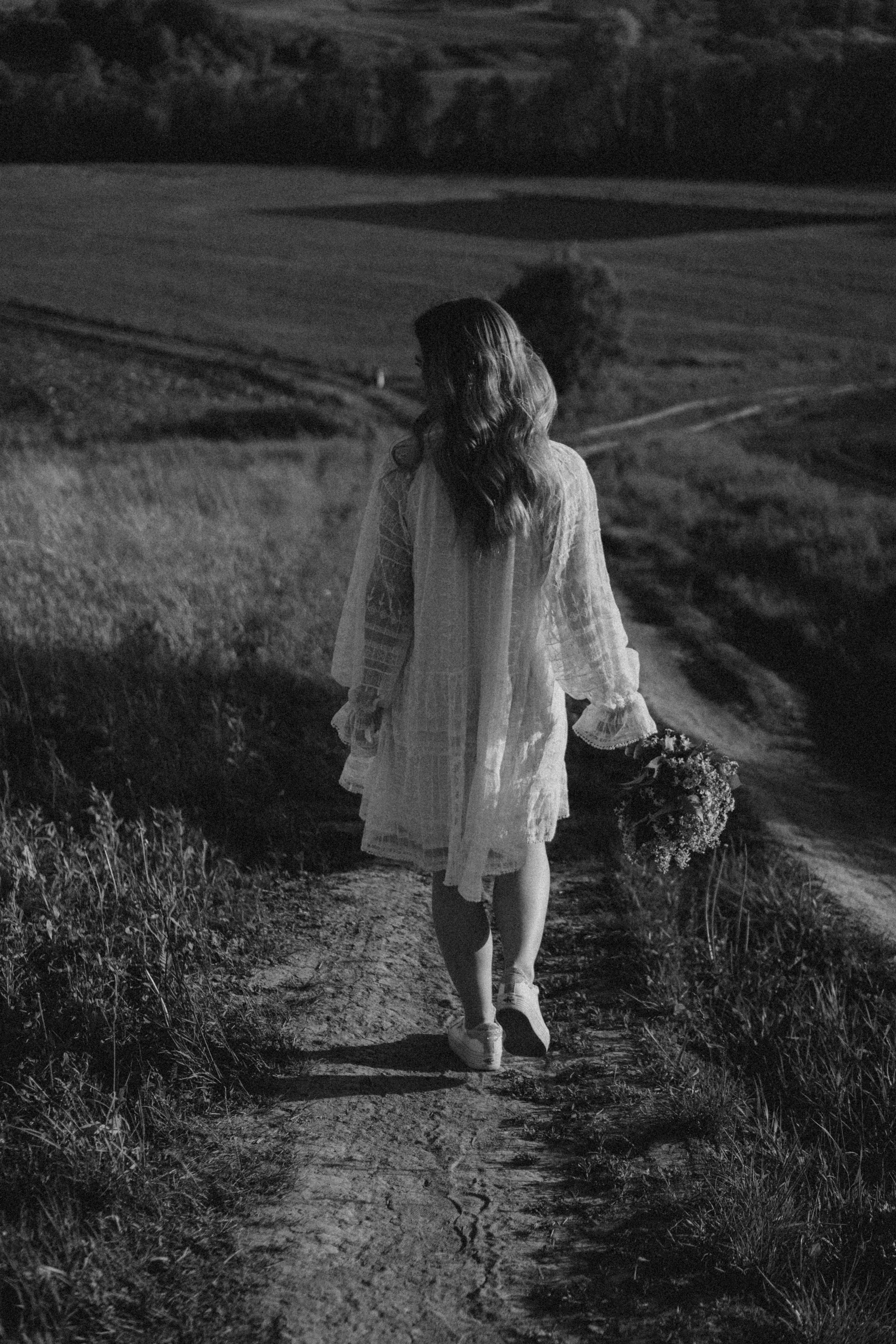 Grayscale Photo of a Woman Walking on Grass Field · Free Stock Photo