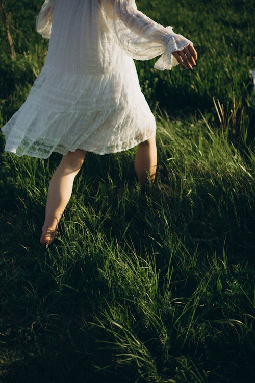 Free Woman in White Lace Dress Walking Through Grass Stock Photo