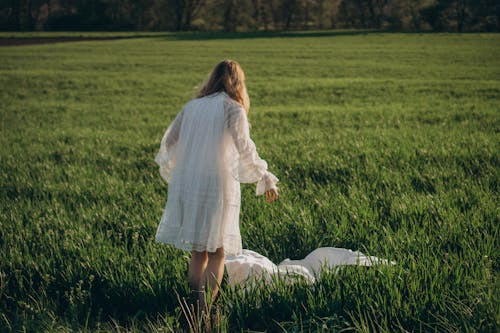 Free Woman in White Dress Standing on Green Grass Field Stock Photo