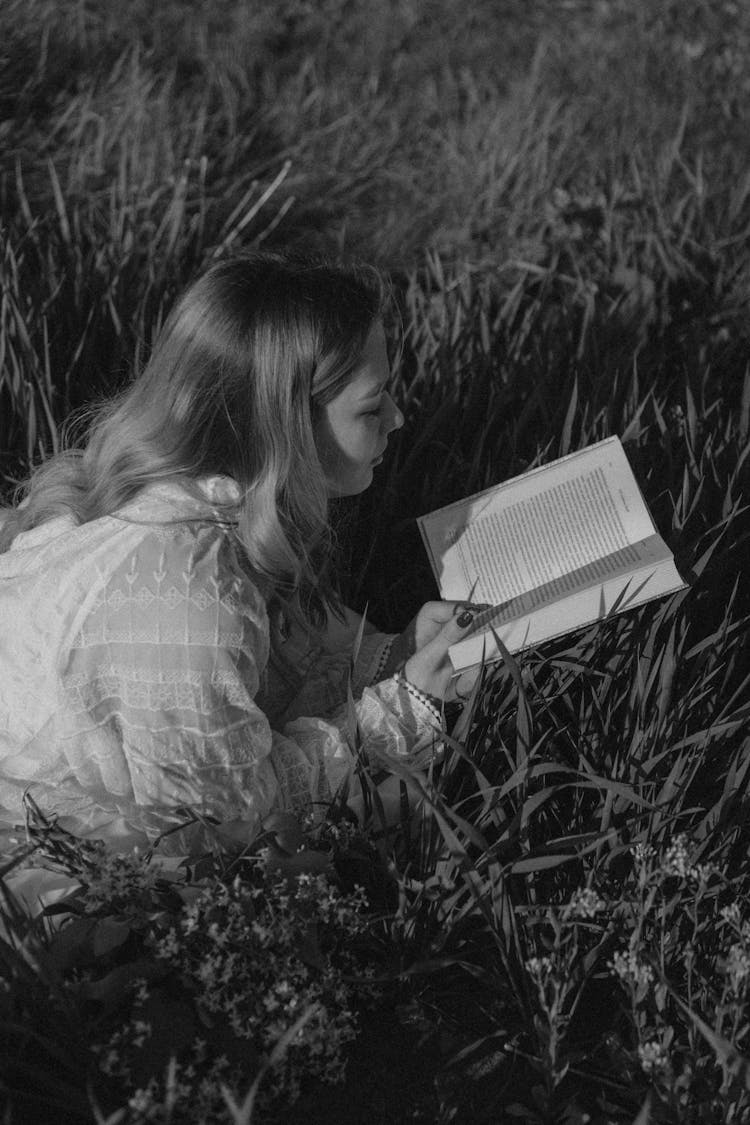 Woman Lying In Field Of Tall Grass Reading Book