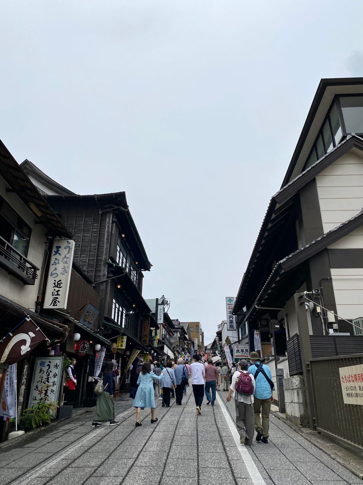 Visitors walking along the stone-paved Okage Yokocho street in Ise, lined with traditional wooden shops