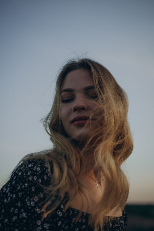 Free Elegant woman with flowing hair poses outdoors at twilight, embracing the serene atmosphere. Stock Photo