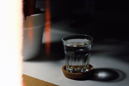 Free Clear Drinking Glass of water on Brown Coaster Stock Photo