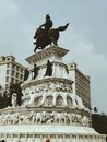 Black Statue of Man Riding Horse on a Concrete Pedestal