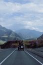 Car with Bicycles on Roof Rack Heading Towards Mountains