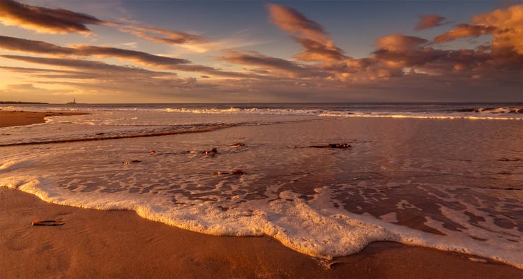 Sea Waves Crashing On Shore During Sunset