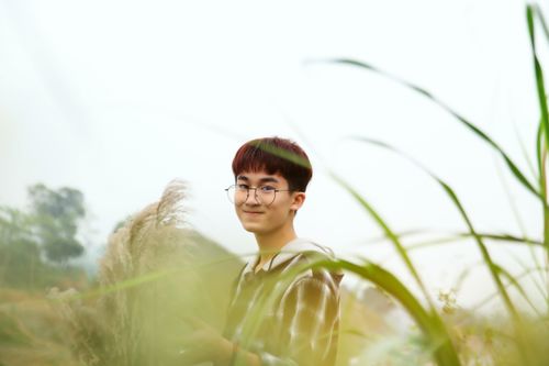 Free A smiling teenager with glasses in a grassy field, exuding joy in an outdoor setting. Stock Photo