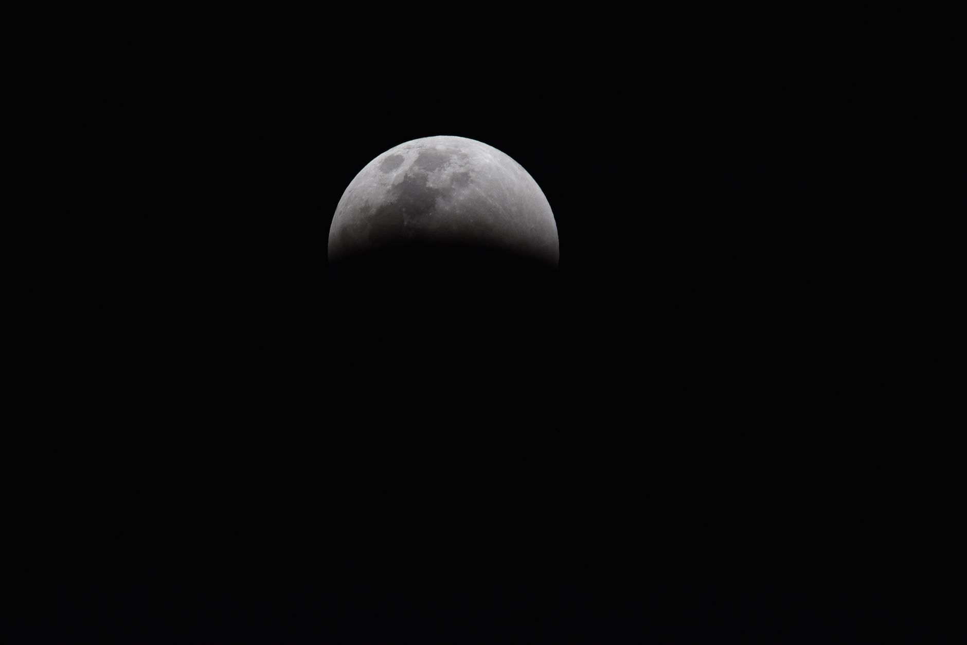 Dramatic view of a partial lunar eclipse showcasing the moon's shadowed surface against a dark sky.