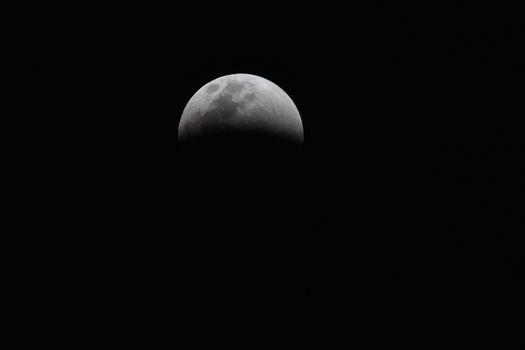 Dramatic view of a partial lunar eclipse showcasing the moon's shadowed surface against a dark sky.