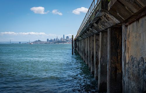 Free A striking view of San Francisco's skyline from beneath a weathered pier overlooking the bay. Stock Photo