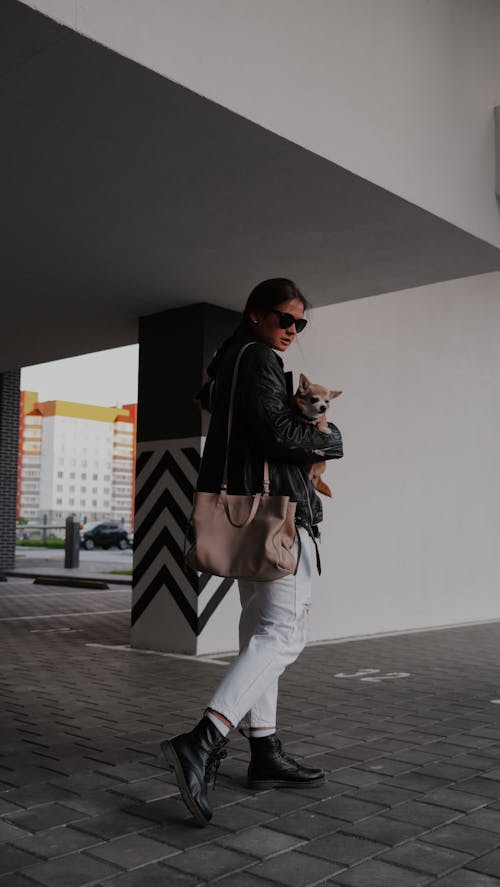 Girl in Black Leather Jacket Wearing Sunglasses Carrying a Dog