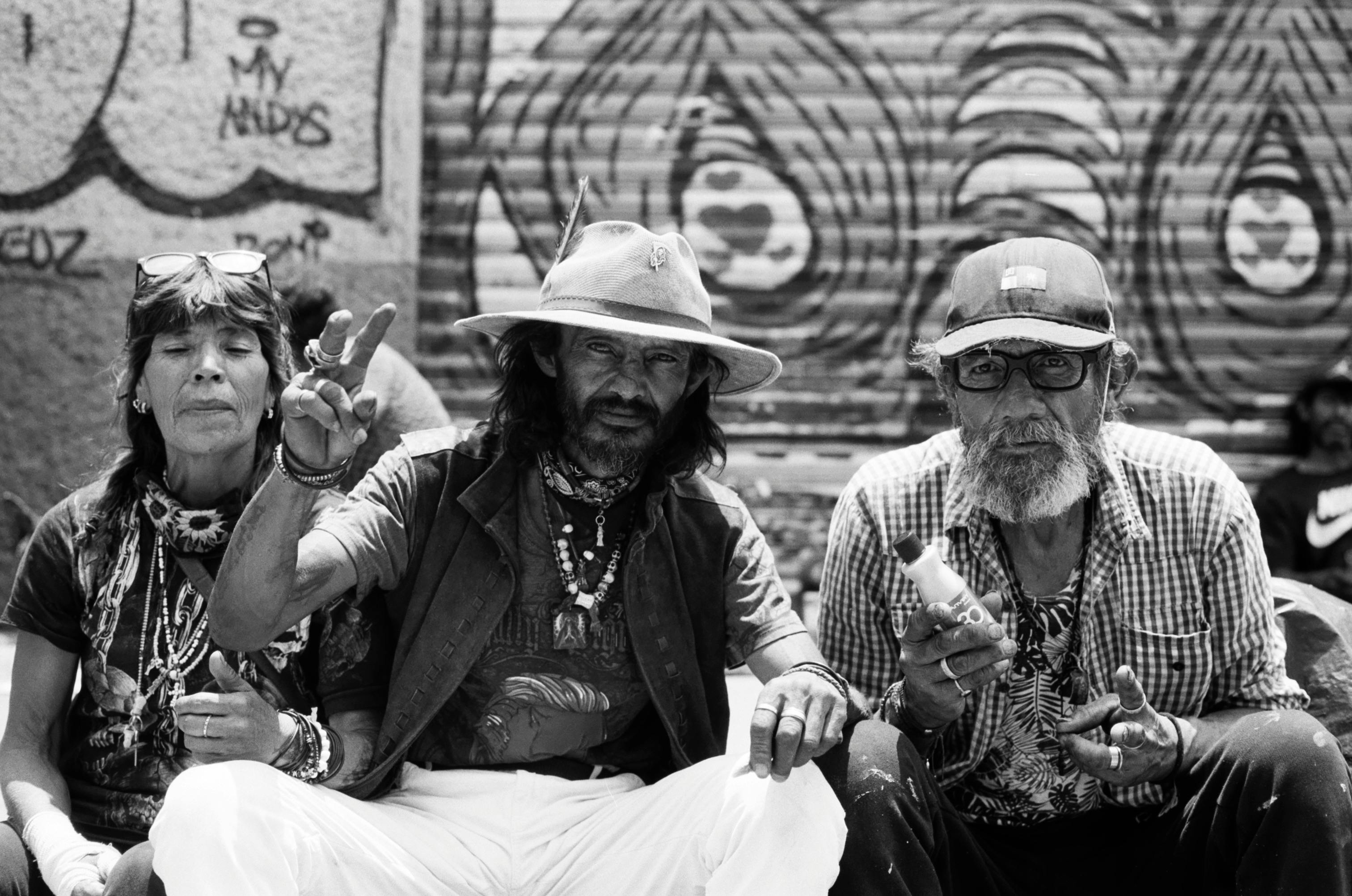 Black and white photo of three senior adults against a graffiti backdrop, embracing urban street art culture.