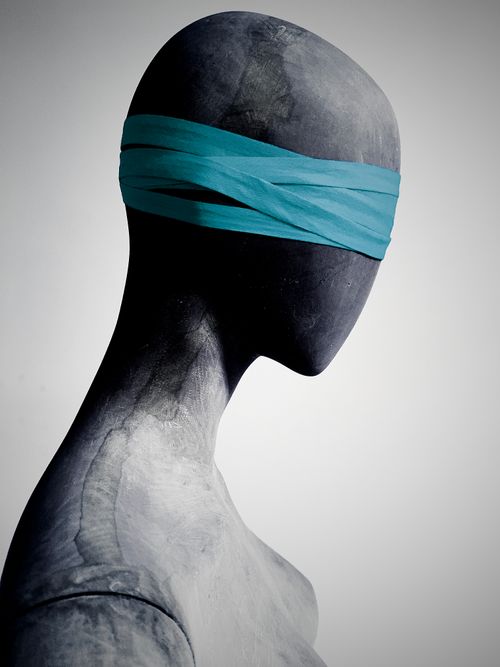 Free Side view of a gray sculpture wearing a teal blindfold, captured in a minimalist style. Stock Photo