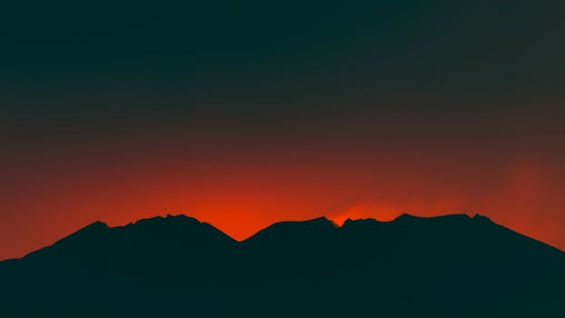 Silhouette of mountains in Japan against a vivid red sunset sky, creating a striking natural landscape.