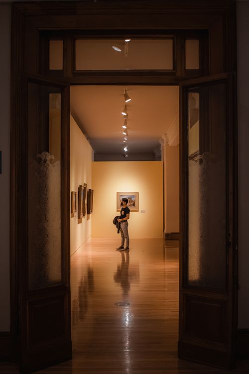 Free Person explores a dimly lit art gallery in Mexico City, framed by a doorway. Stock Photo