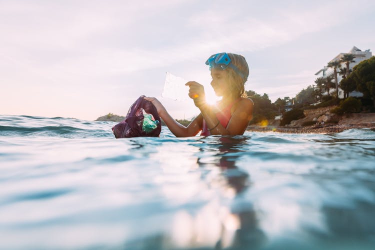 Girl Collecting Garbage In Sea