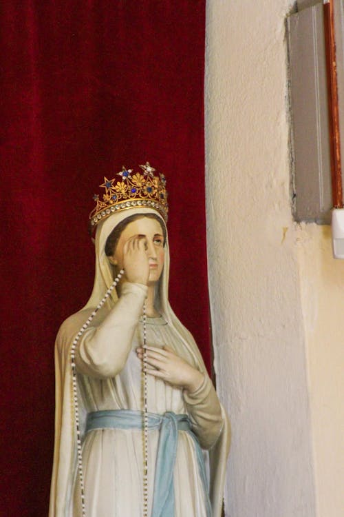 Virgin Mary in a Crown Figurine against Red Curtain