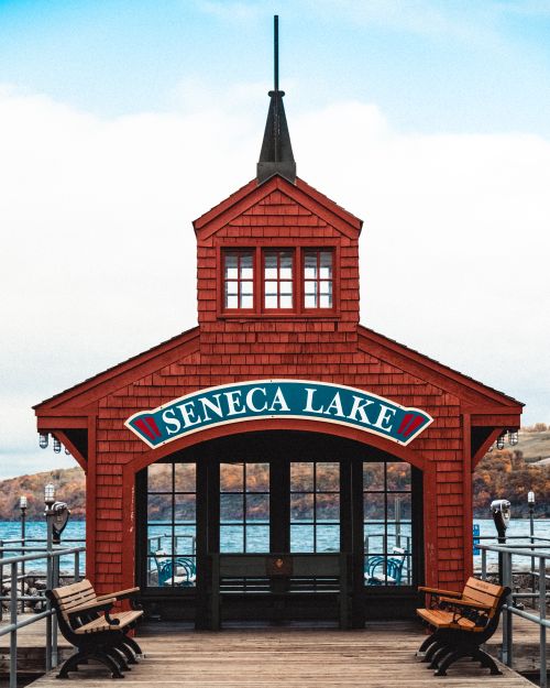 Free Scenic view of the iconic red pavilion on Seneca Lake dock with benches and blue waters. Stock Photo