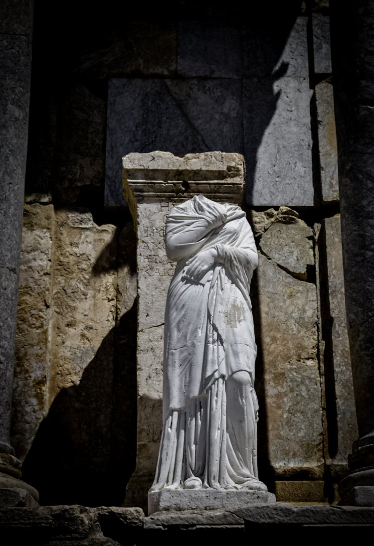 Headless Statue Beside Concrete Wall