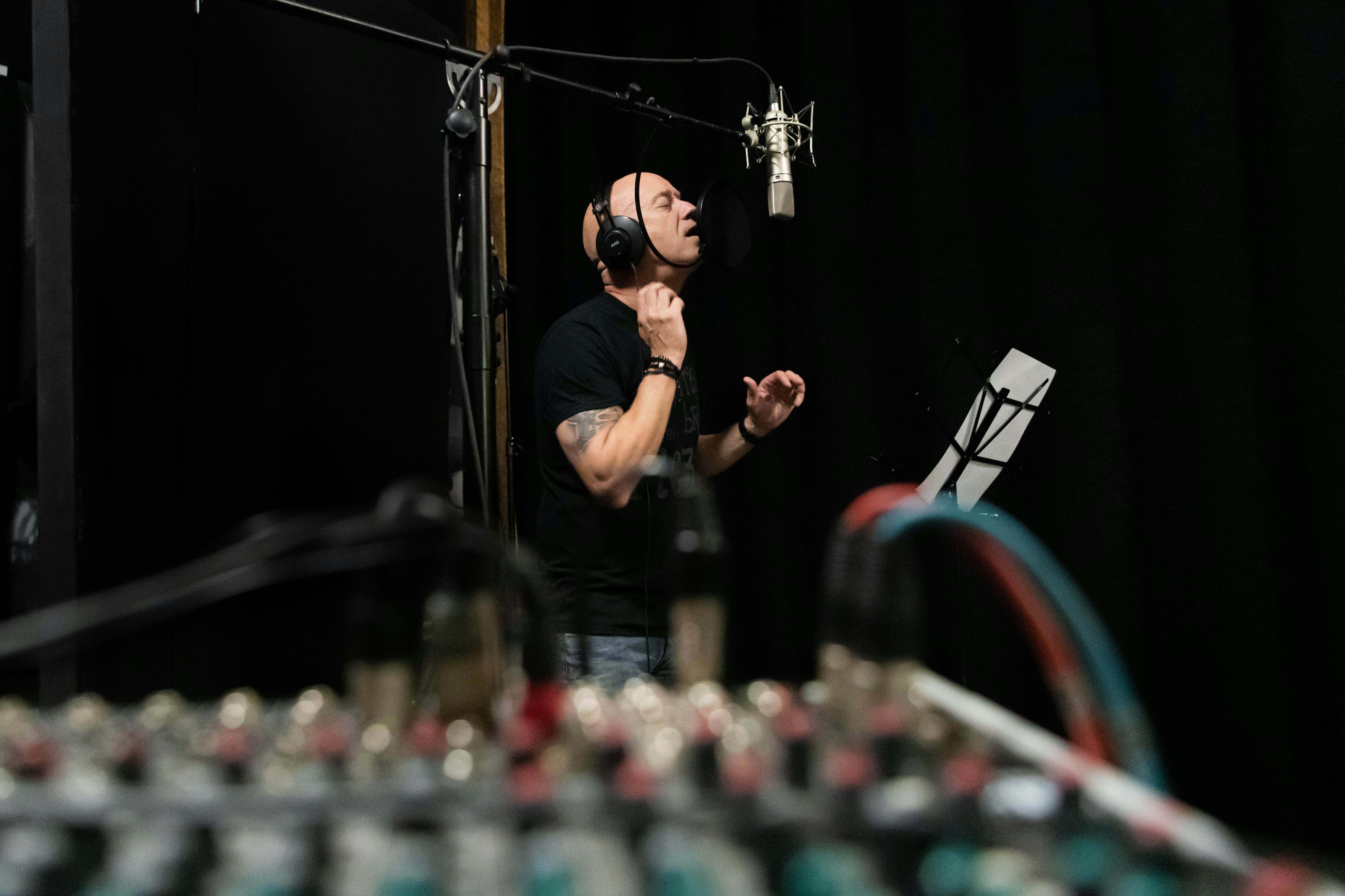 A vocalist intensely performing in a professional recording studio setting.