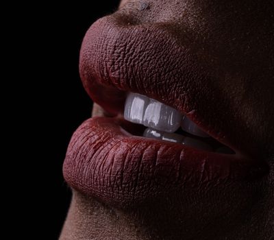 A detailed close-up of lips with red lipstick and white teeth, highlighting texture and expression.