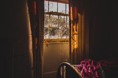 A cozy bedroom with sunlight streaming through the window onto a vintage bed.