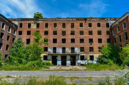 Free Explore the graffiti-covered facade of an abandoned brick building surrounded by greenery in Pécs, Hungary. Stock Photo
