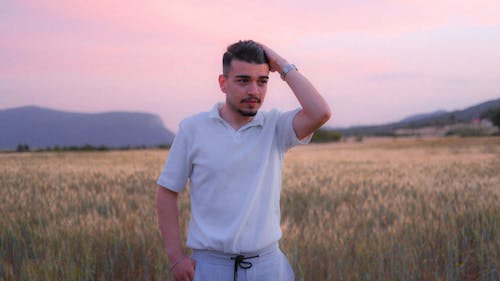 Man in White Polo Shirt Standing on Grass Field