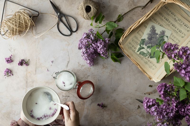 Elegant flat lay featuring lilacs, music sheets, and crafting tools on a marble surface.