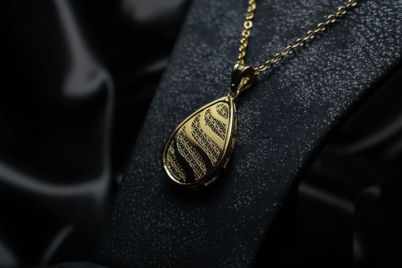 Colgante de oro en forma de gota sobre satén negro