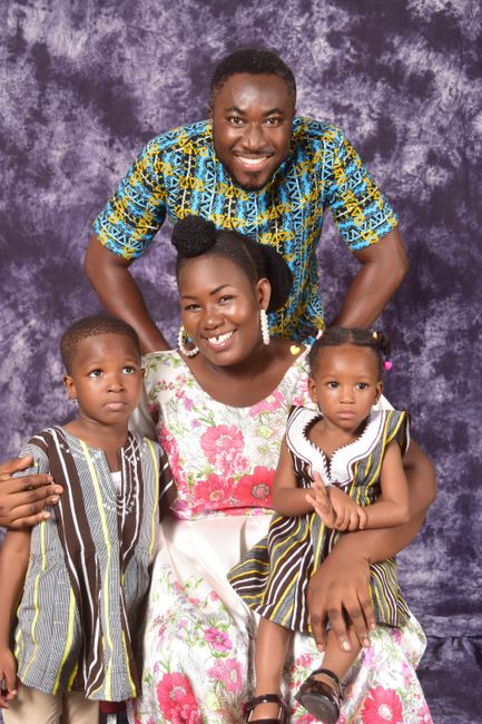A joyful Ghanaian family posing together in traditional attire, exuding warmth and closeness.