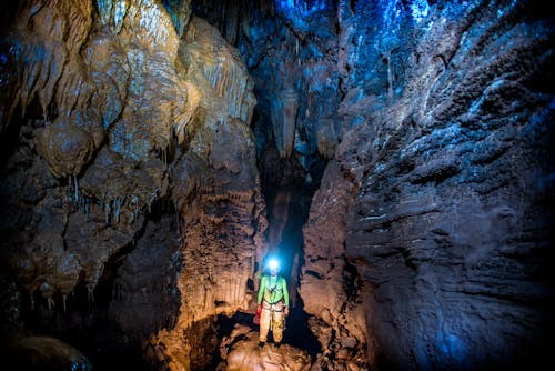 Man Wearing a Head Torch Standing in a Cave