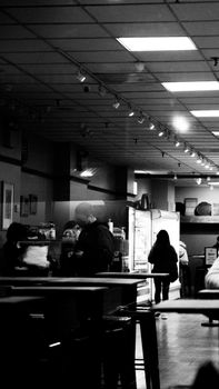 Monochrome view of a cafe interior with people interacting near the counter.