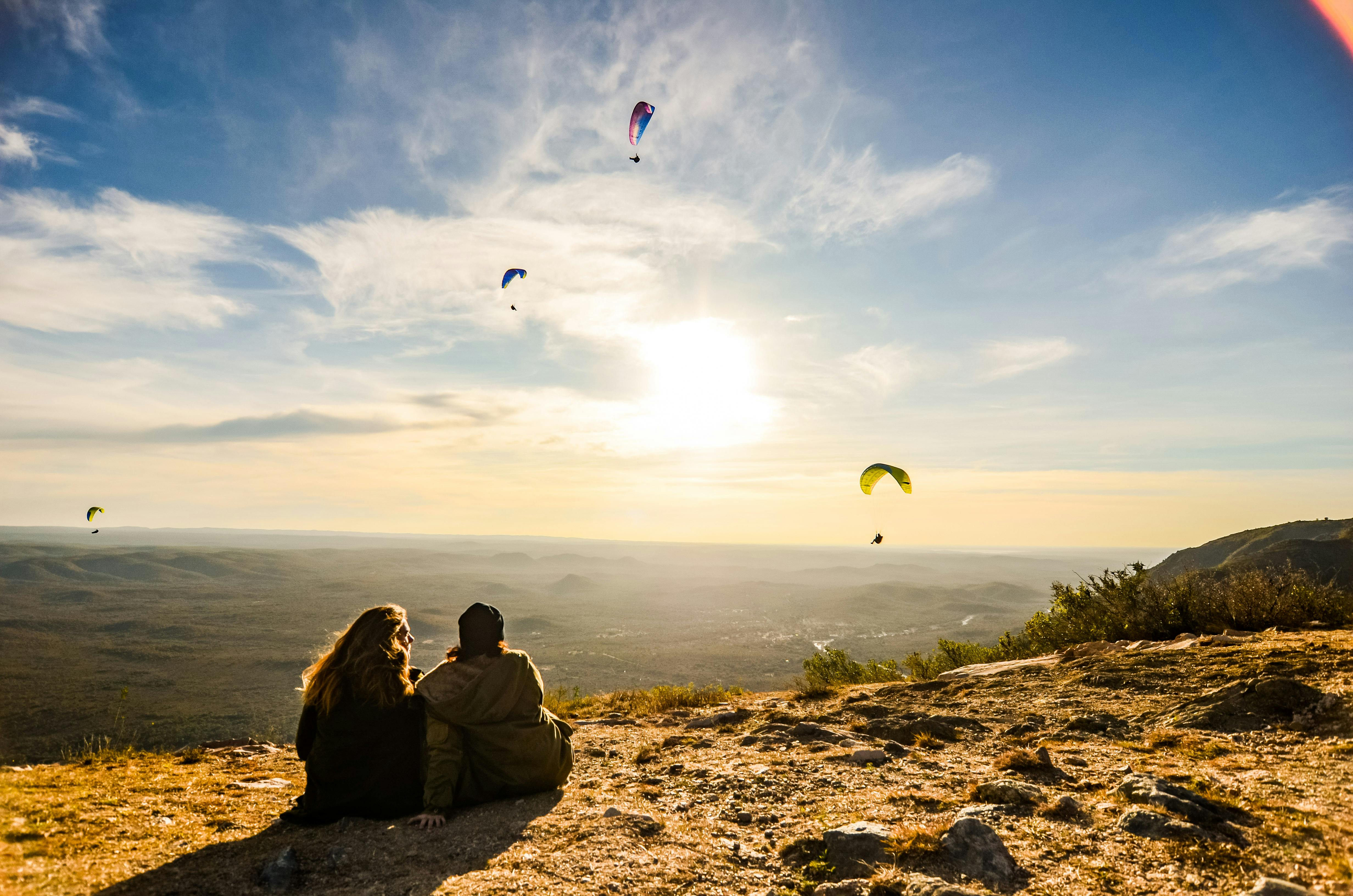 couple looking at para gliders in sky