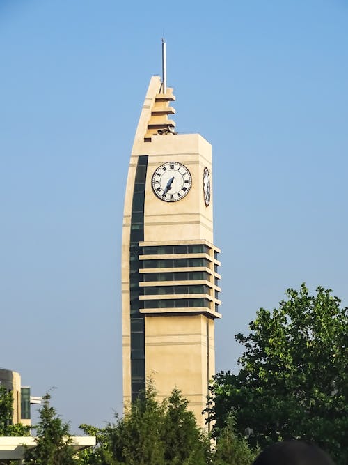 A Concrete Clock Tower With Glass Panels