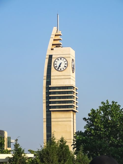 Free Striking modern clock tower with glass panels and clear blue sky backdrop. Stock Photo