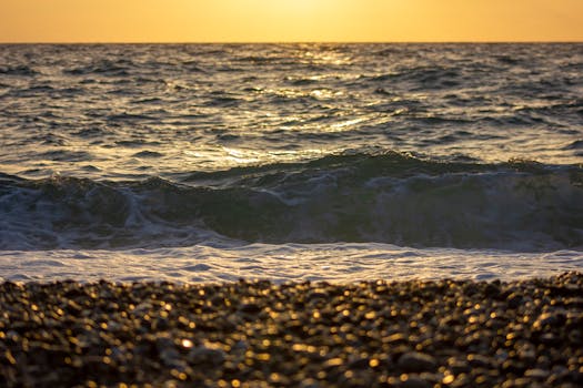 Stunning sunset over a rocky beach in Calabria, Italy, capturing the beauty of rolling ocean waves.