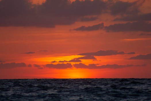 Dramatic orange sunset over the Mediterranean Sea, Calabria, Italy, with dark clouds and vivid colors.