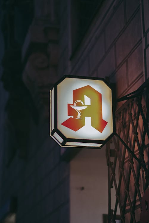 A Lighted Signage Near a Brick Wall With Metal Railing