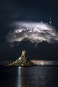 Captivating view of Aci Trezza coast under a stormy sky with lightning at night.