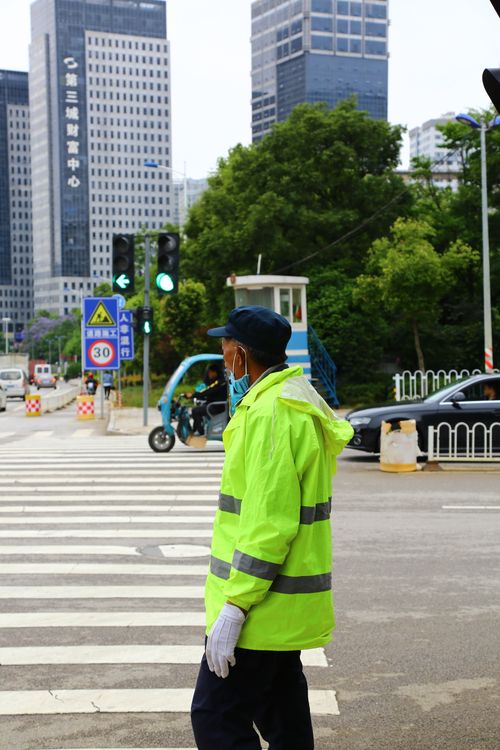 Free A traffic officer in a safety vest monitors a busy street in an urban setting. Stock Photo