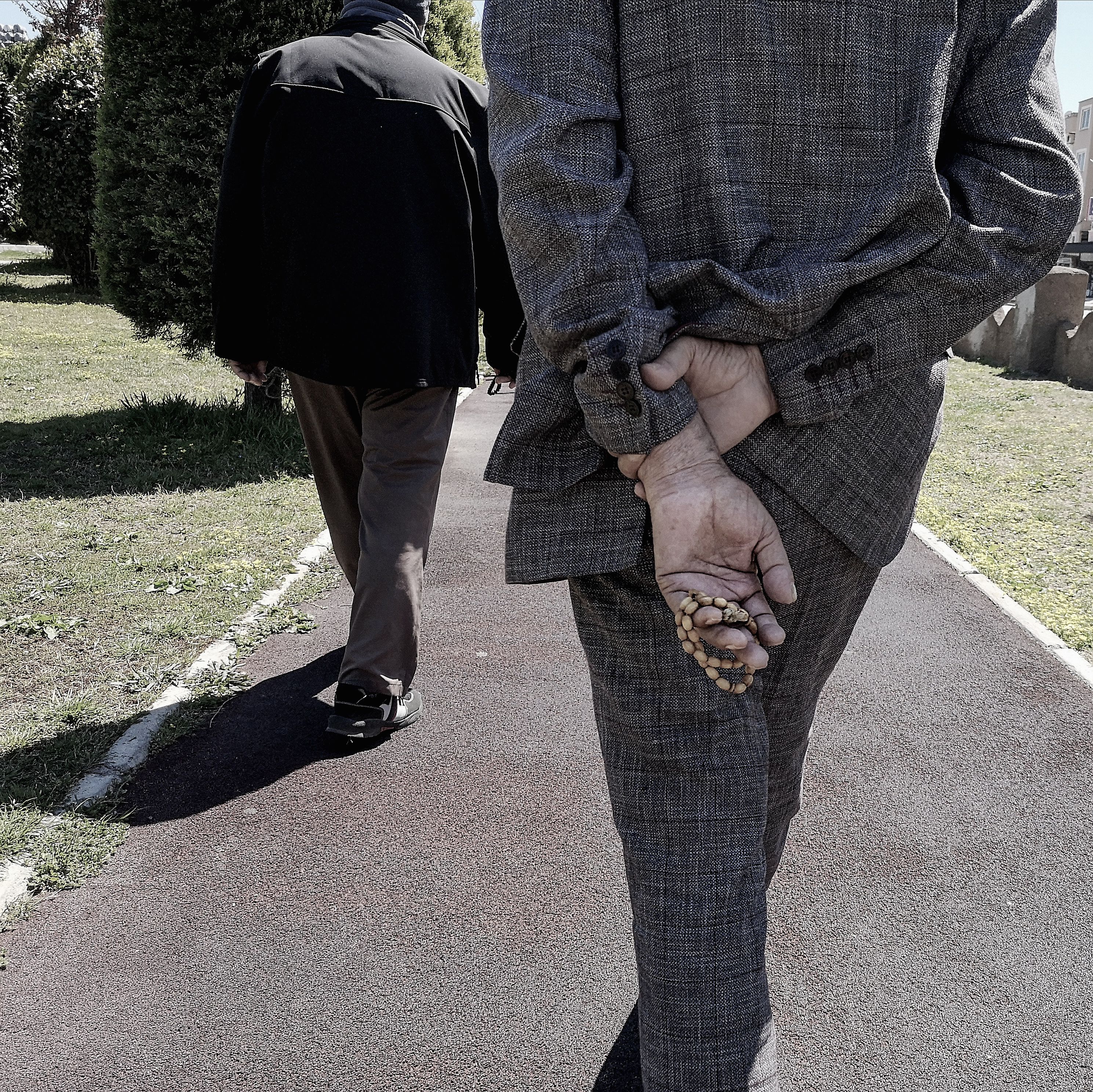 An elderly couple walking through a quiet park on a grey day