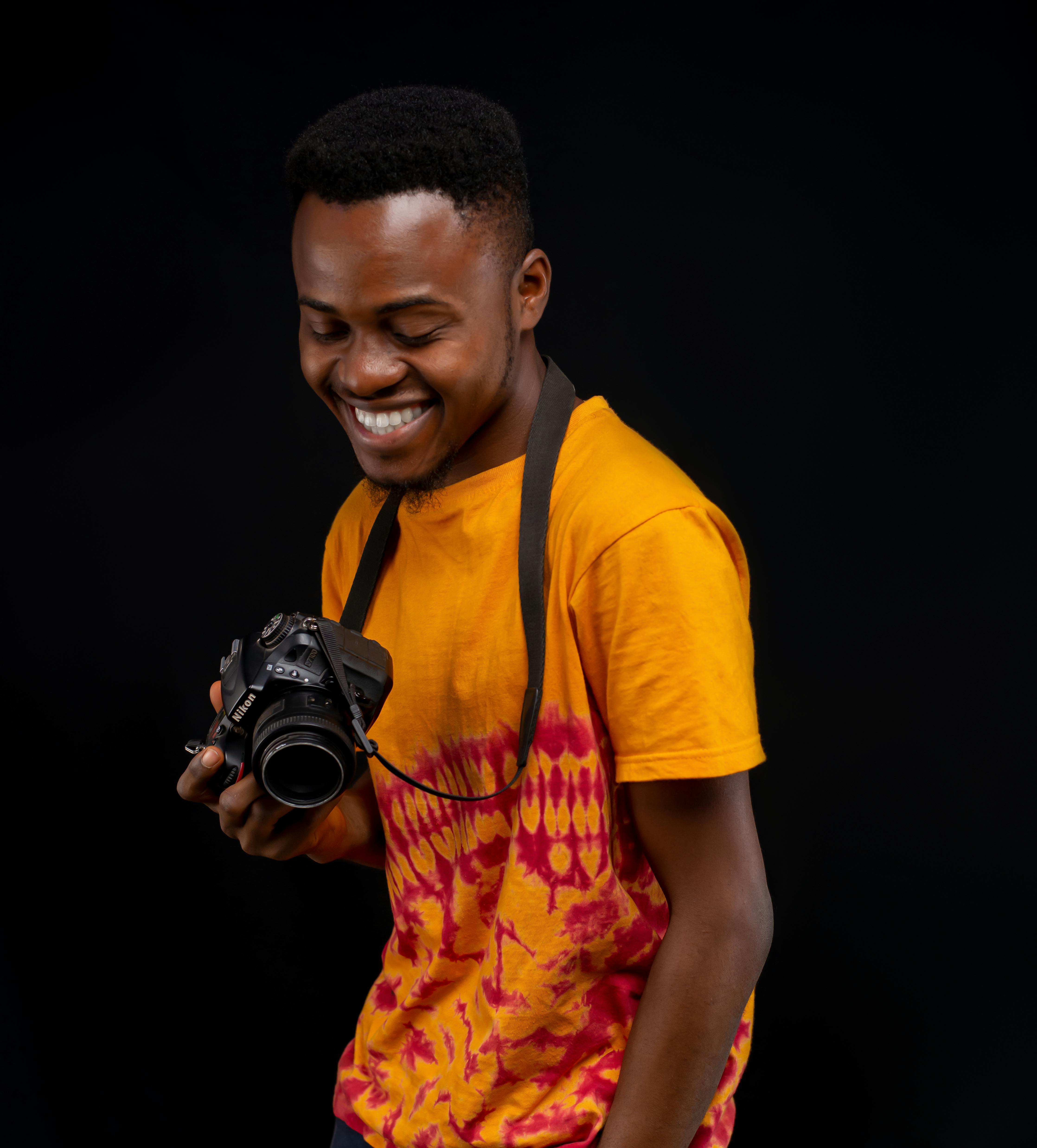 Smiling man holding a DSLR camera in a vibrant studio portrait.