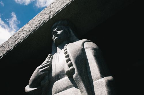 Free A captivating stone statue seen from below against a clear sky, highlighting its intricate artistry. Stock Photo