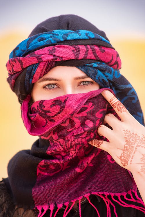 Free Woman in Red and Blue Hijab Covering Her Face With Blue and Red Scarf Stock Photo