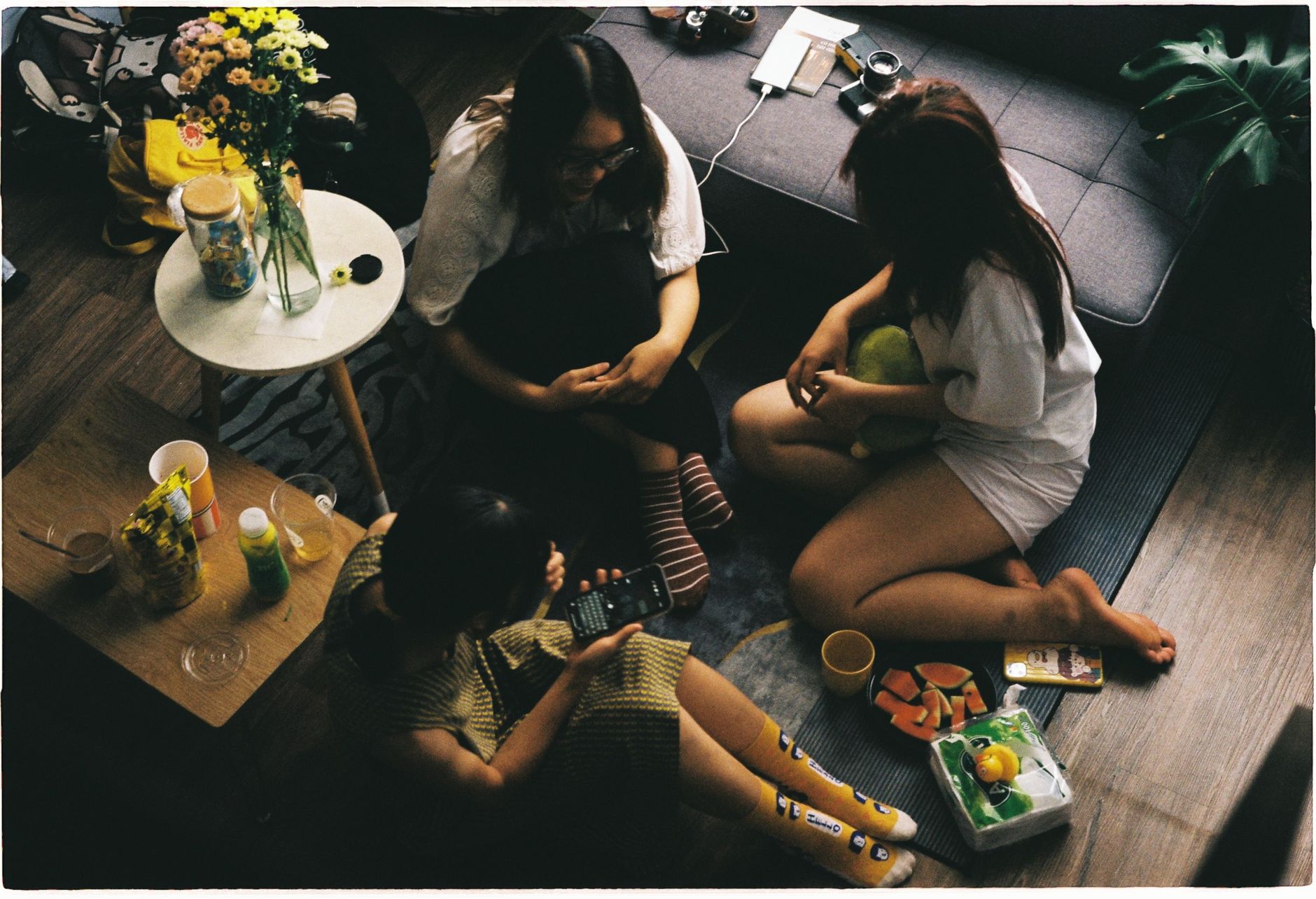 Three friends enjoying a cozy evening indoors with snacks and drinks.