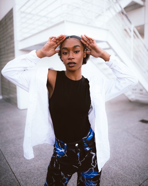 Fashionable woman in a black top and patterned pants posing confidently outdoors.