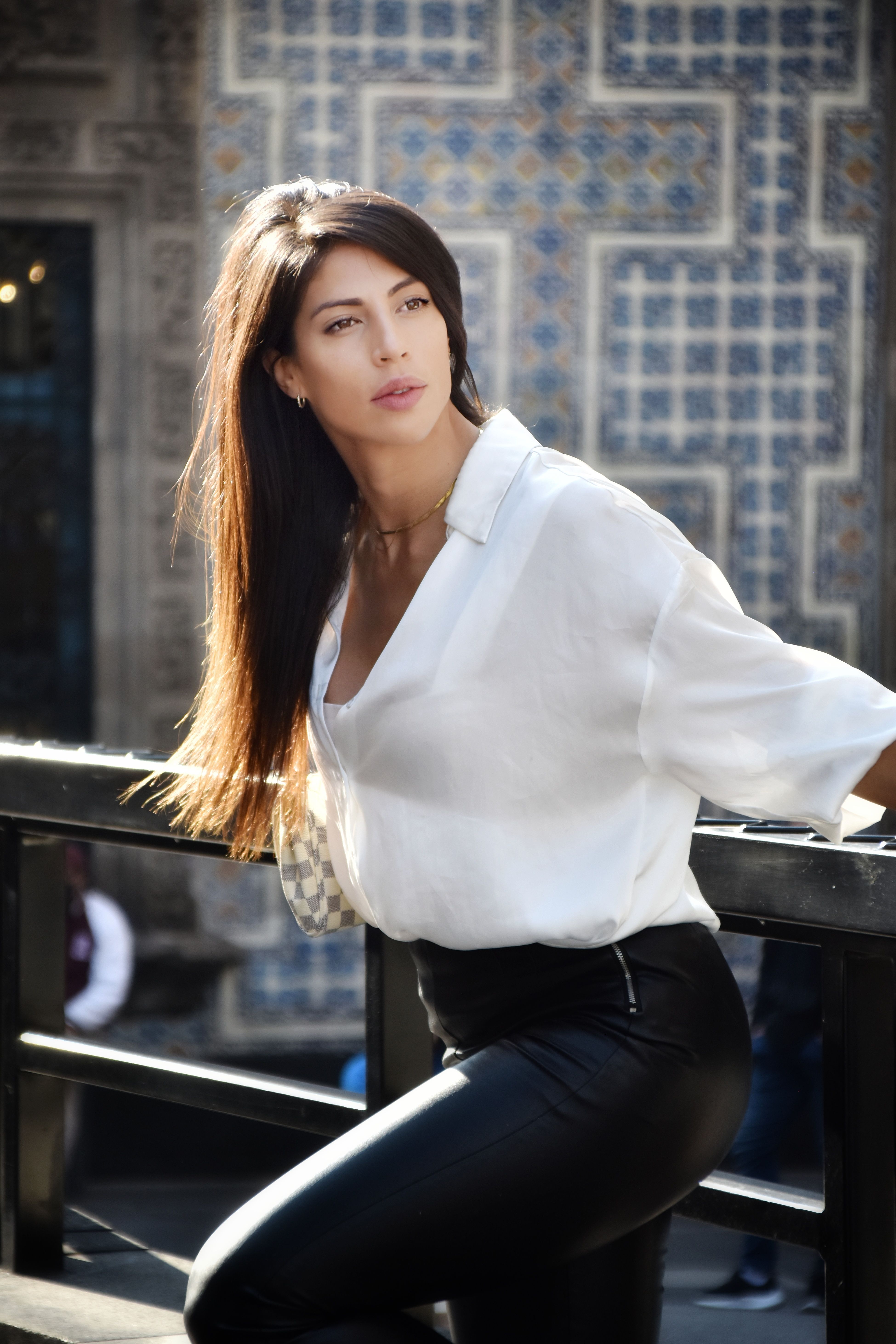 A stylish woman leaning on a fence in Mexico City, showcasing modern fashion outdoors.