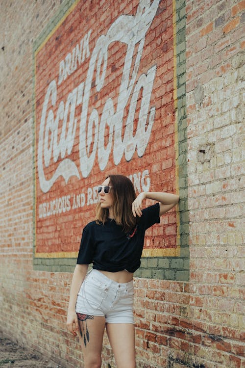 Woman Standing next to a Wall with Coca Cola Ad