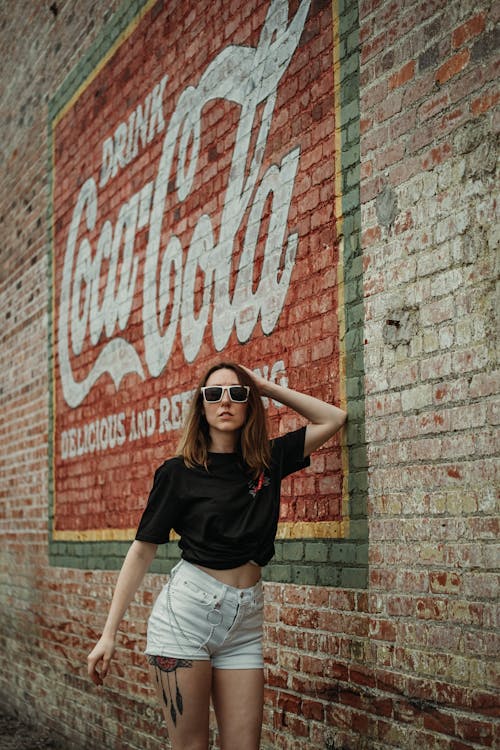 Photo of Woman Standing by the Wall with a Coca Cola Ad